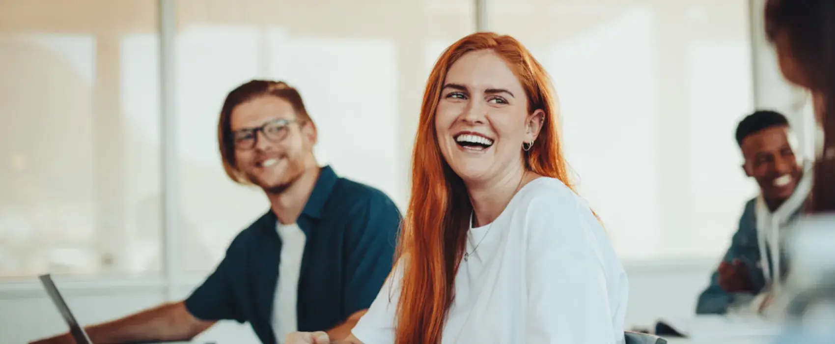 Women and man laughing at a desk