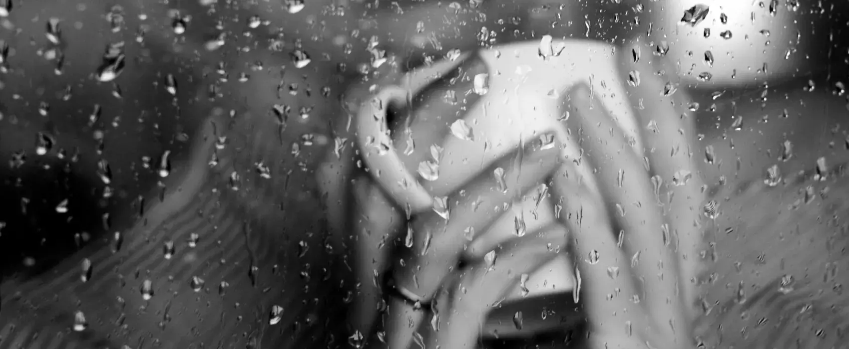 Women drinking a hot drink behind a rain covered window